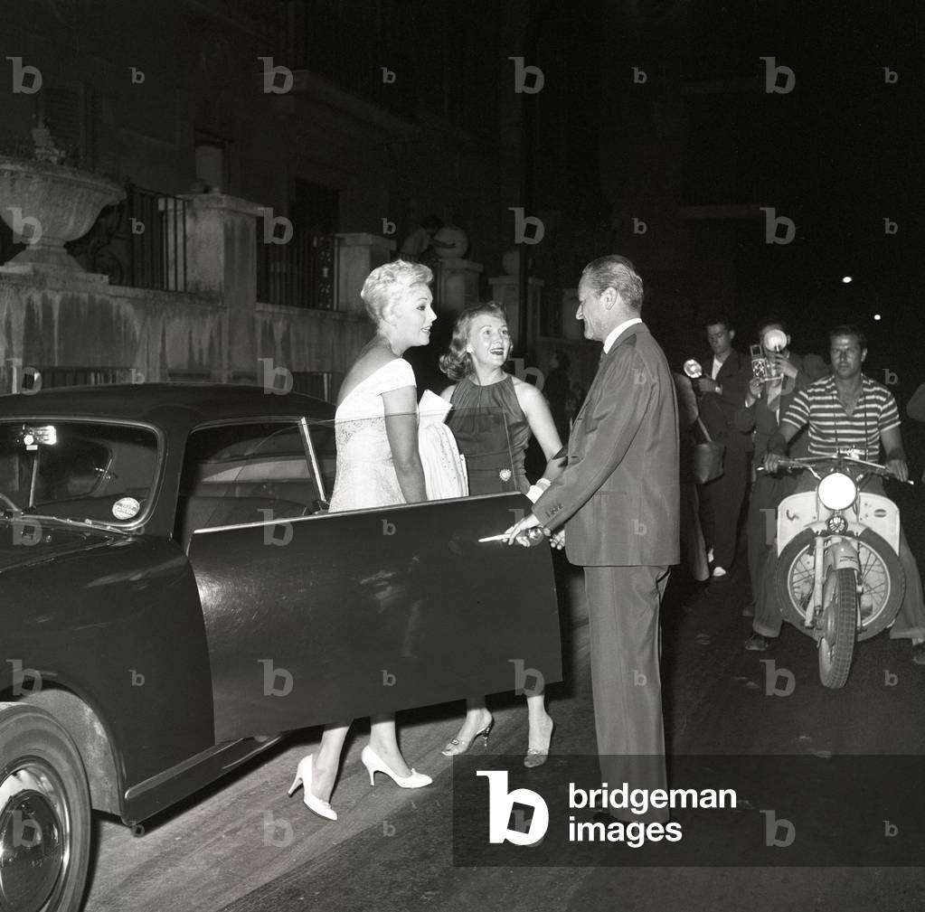 Mario Bandini Pallavicini opening Kim Novak's car door, Italy, 1956 (b/w photo)
