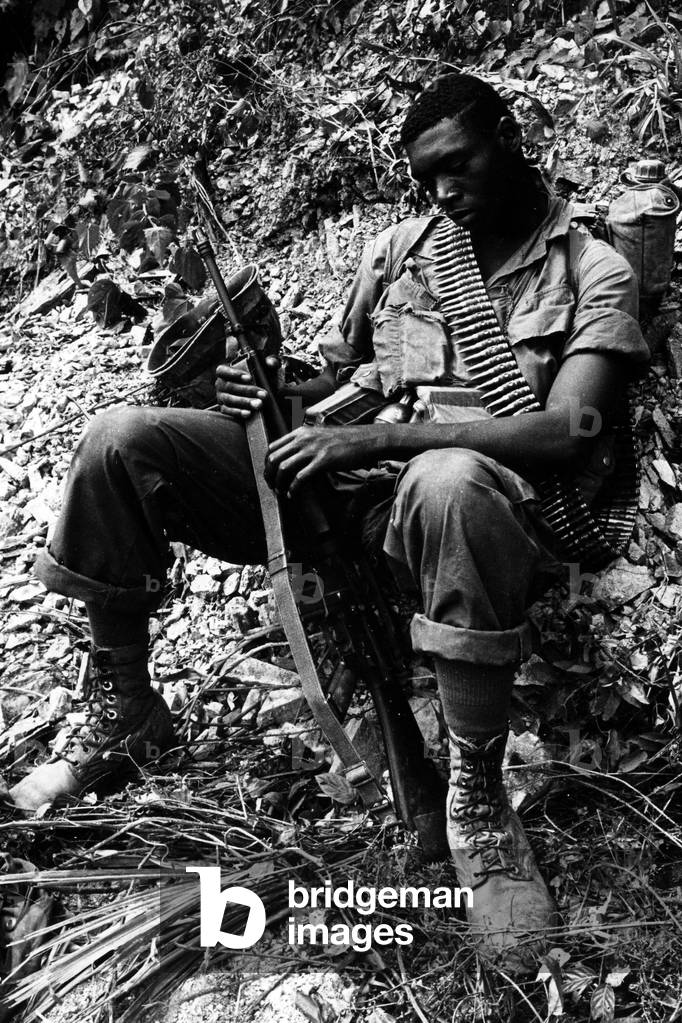An armed US military seated on the ground