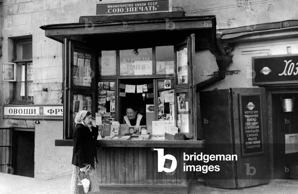 Two women chat at the newspaper kiosk