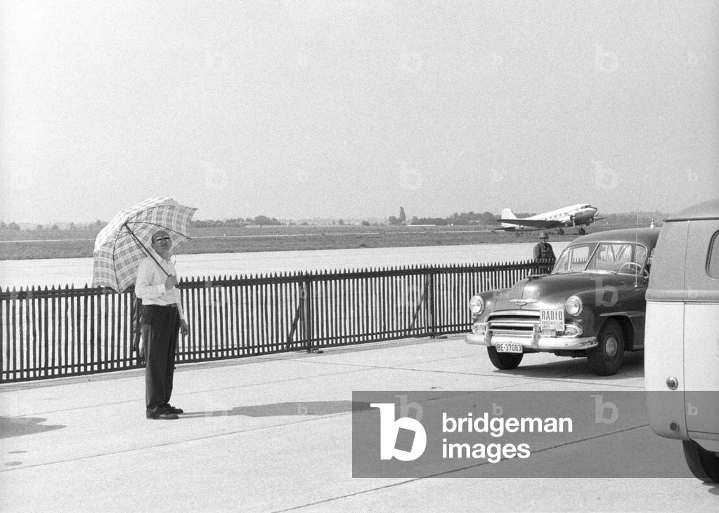 A man holding an umbrella beside the landing field of the Geneva Airport, Geneva, Switzerland
