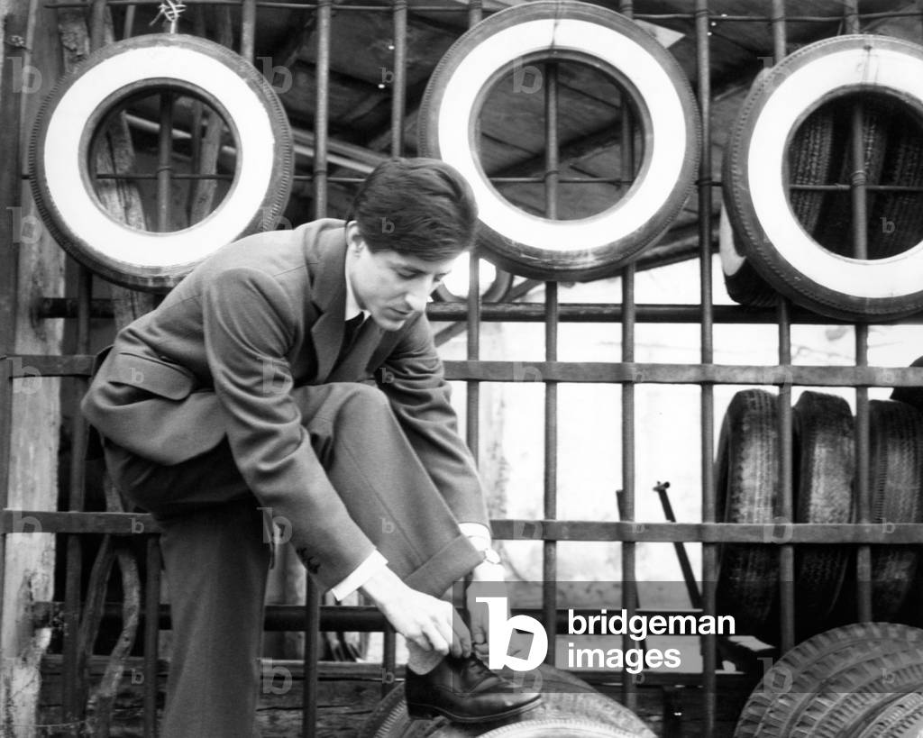 Giorgio Gaber lacing up his shoe, 1963 (b/w photo)