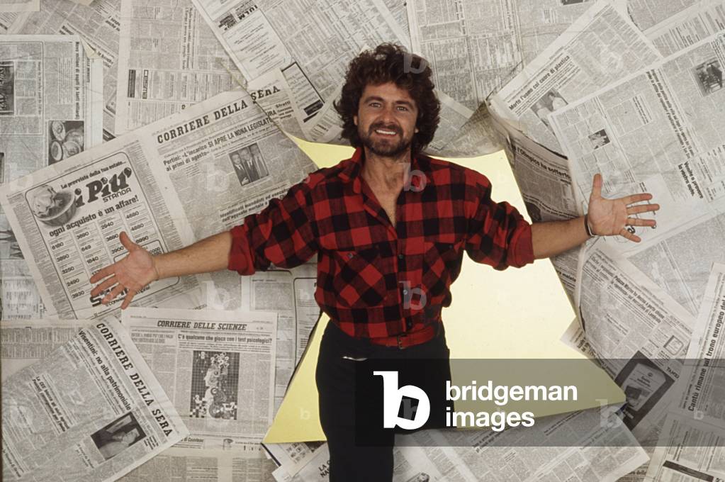 The comedian Beppe Grillo surrounded by newspapers, 1983 (b/w photo)