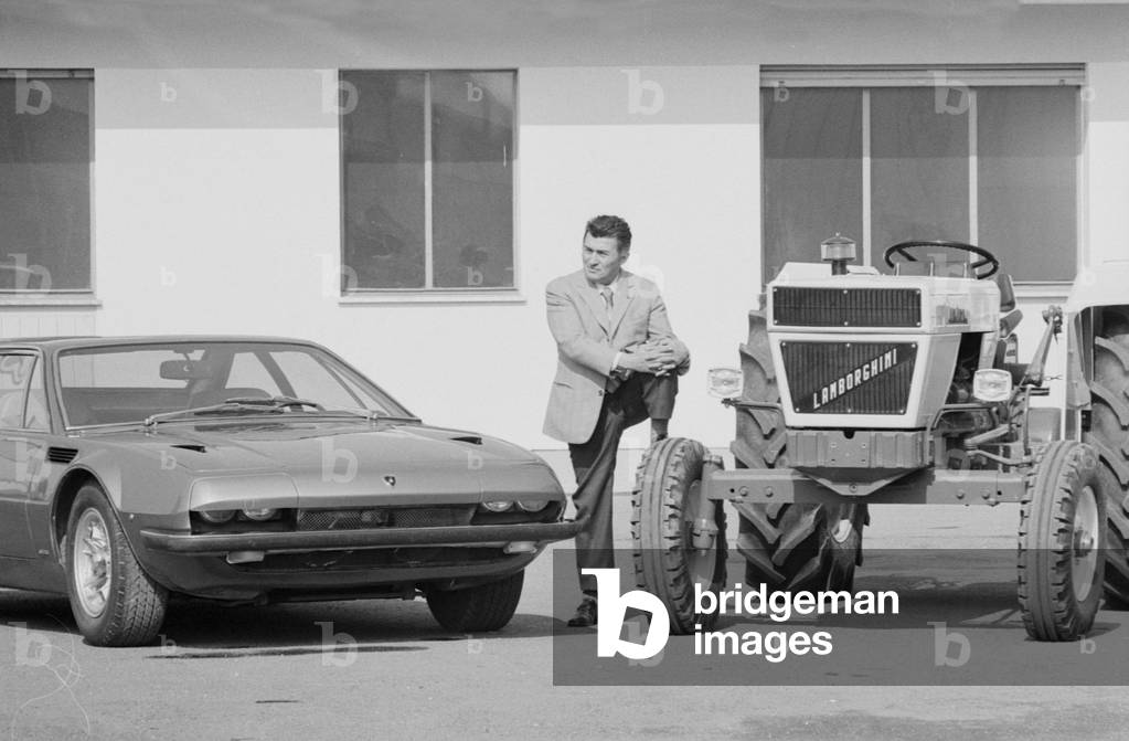 Ferruccio Lamborghini standing between a Lamborghini Jarama and a tractor, Italy, 1970 (b/w photo)