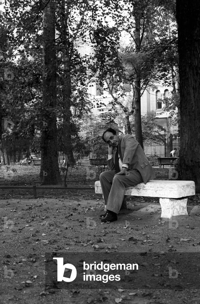 Alfonso Gatto sitting on a stone bench, in a park