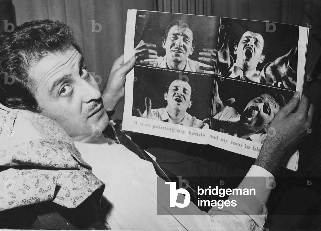 Domenico Modugno showing some photos on a magazine