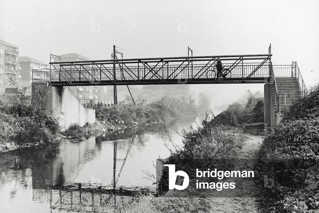 Man with his bicycle crossing a footbridge