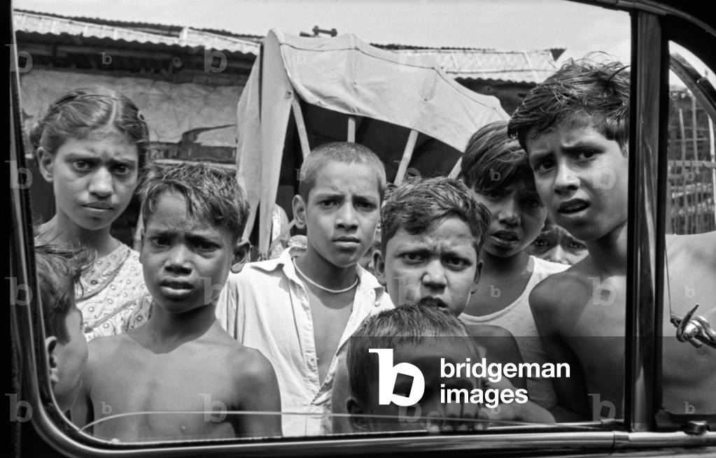 A group of Indian children looking inside a car through the window, Kolkata, India, 1962 (b/w photo)