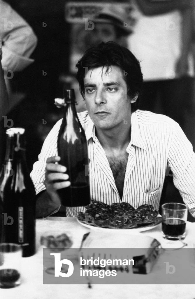 Giancarlo Giannini with a charcuterie plate and a bottle of wine
