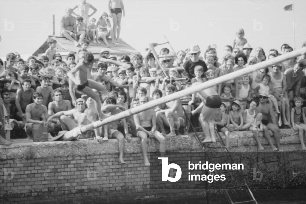 15th August 1969 - Bathers flock on the jetty to see the balancing game on the pole, Italy, 1969 (b/w photo)