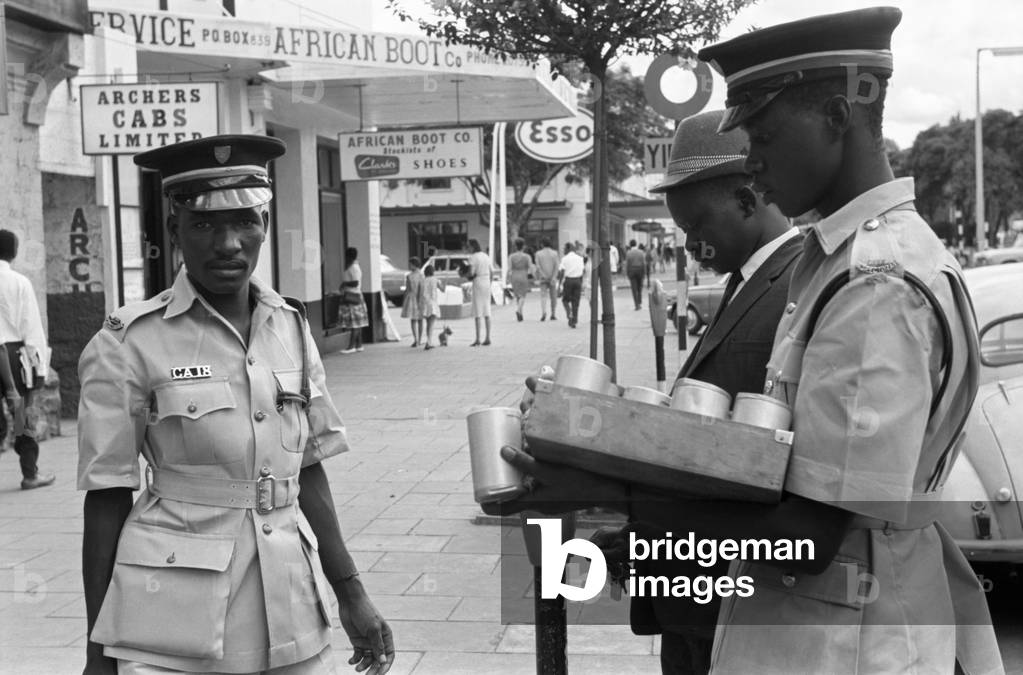African policemen in uniform patrolling a street, Africa, April 1965 (b/w photo)