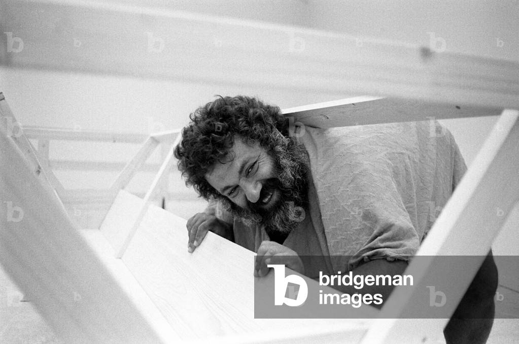 Menashe Kadishman smiling through some wood planks