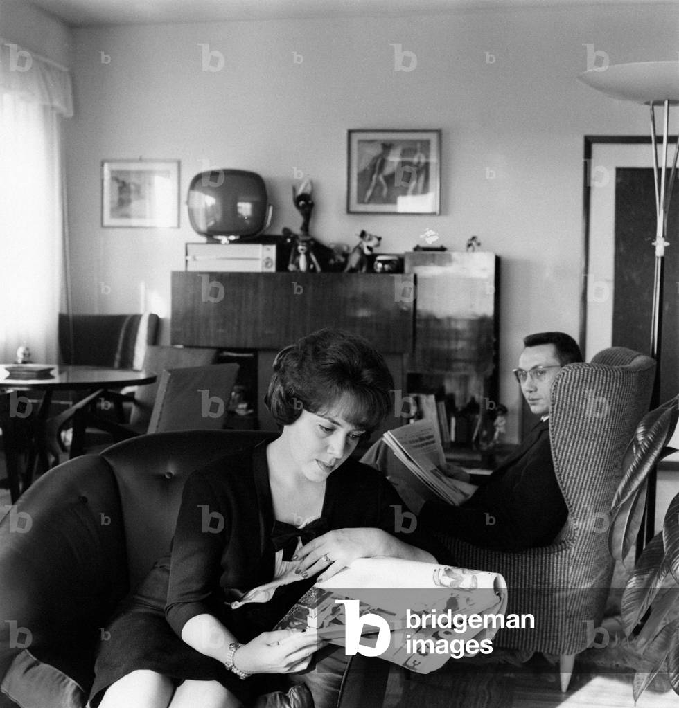 Jula De Palma and her husband Carlo Lanzi are sat down on armchairs and are reading newspapers, 1961 (b/w photo)