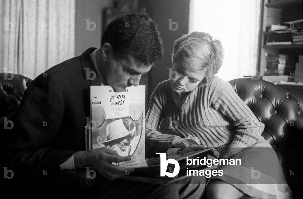 Rita Pavone and Teddy Reno watching some records covers