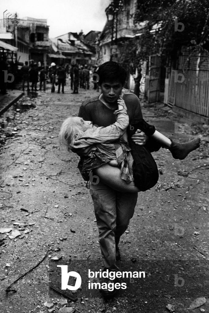 A young Vietnamese carrying an elderly lady in his arms