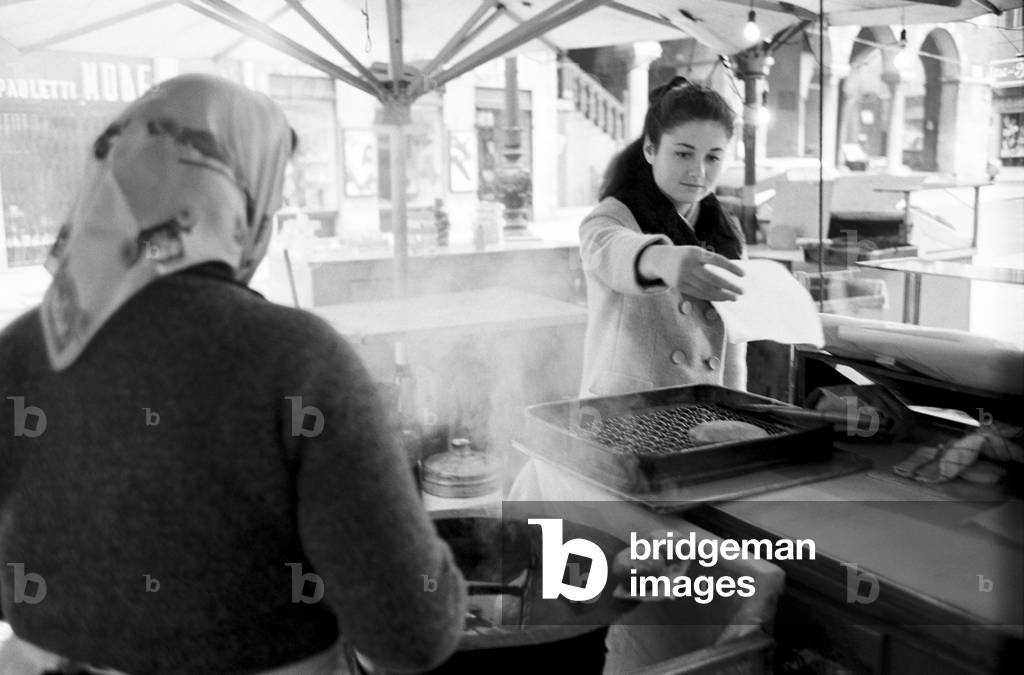 Gigliola Cinquetti is taking a fried panzarotto from a grill in a stall