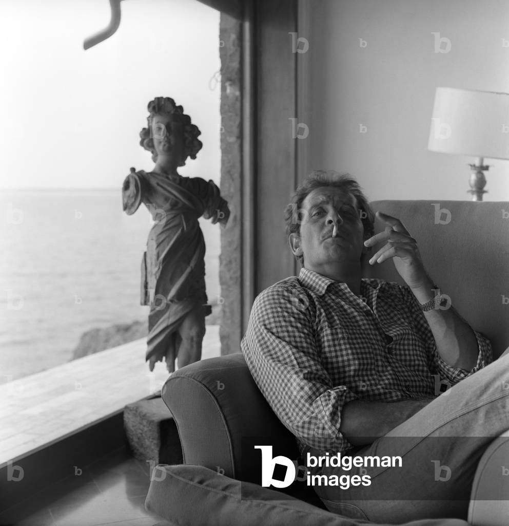 Domenico Modugno smokes a cigarette, sunk in an armchair