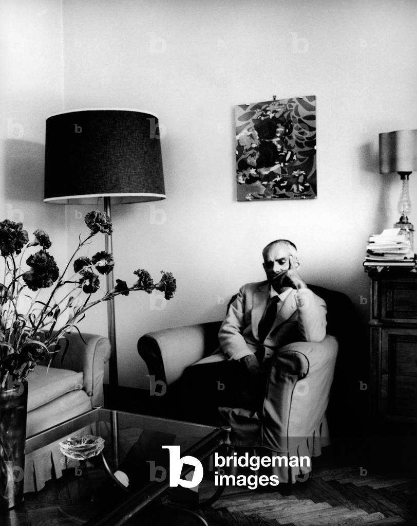 Writer Alberto Moravia, thoughtful, sits in an armchair, Rome, Italy, 1962
