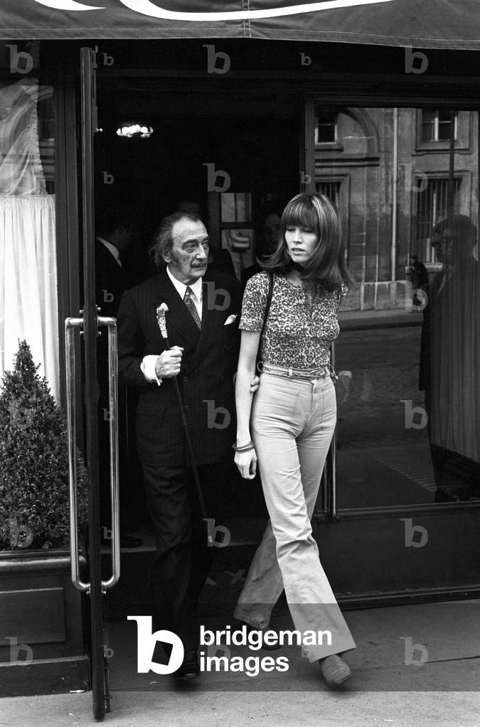 Amanda Lear and Salvador Dali coming out of a restaurant, Italy, 1960 (b/w photo)