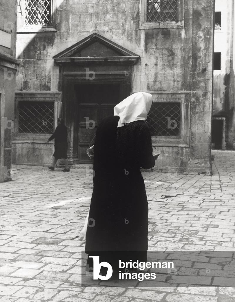 A woman wearing the traditional white headscarf, in a little square of Sebenico
