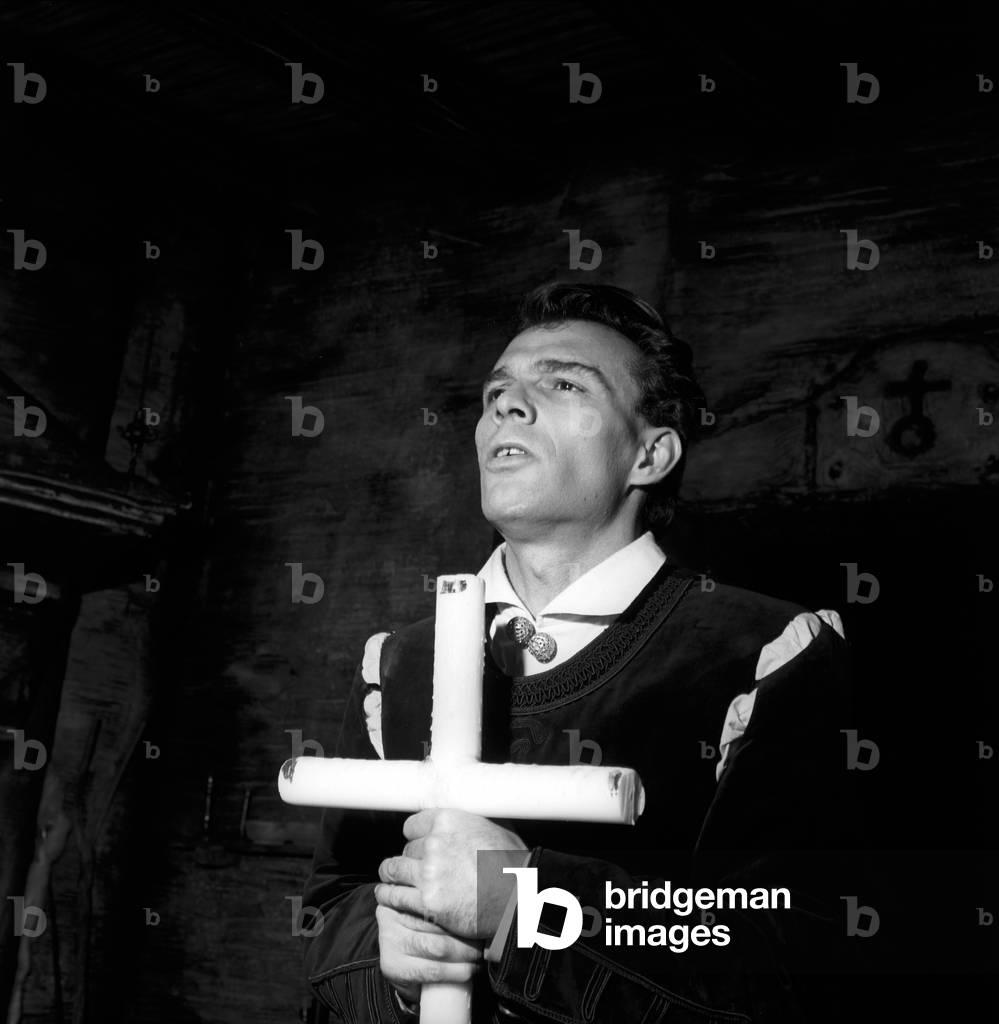 Giorgio Albertazzi with a cross in his hands in a theatre performance, 1957 (b/w photo)