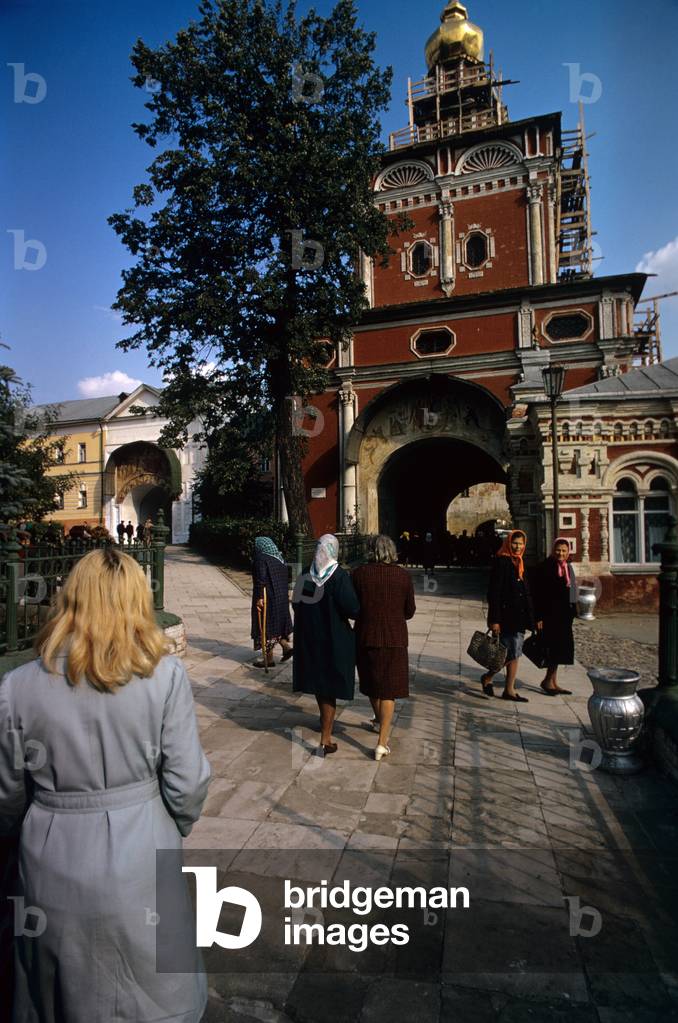 Some pilgrims walking near the frescoed entrance to the Trinity Lavra of Saint Sergius in Zagorsk, Zagorsk, Russian Federation