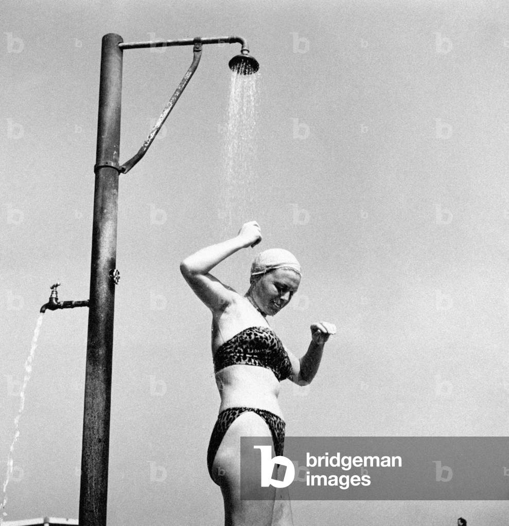 A young woman in swimsuit having a shower, Italy, 1953 (b/w photo)