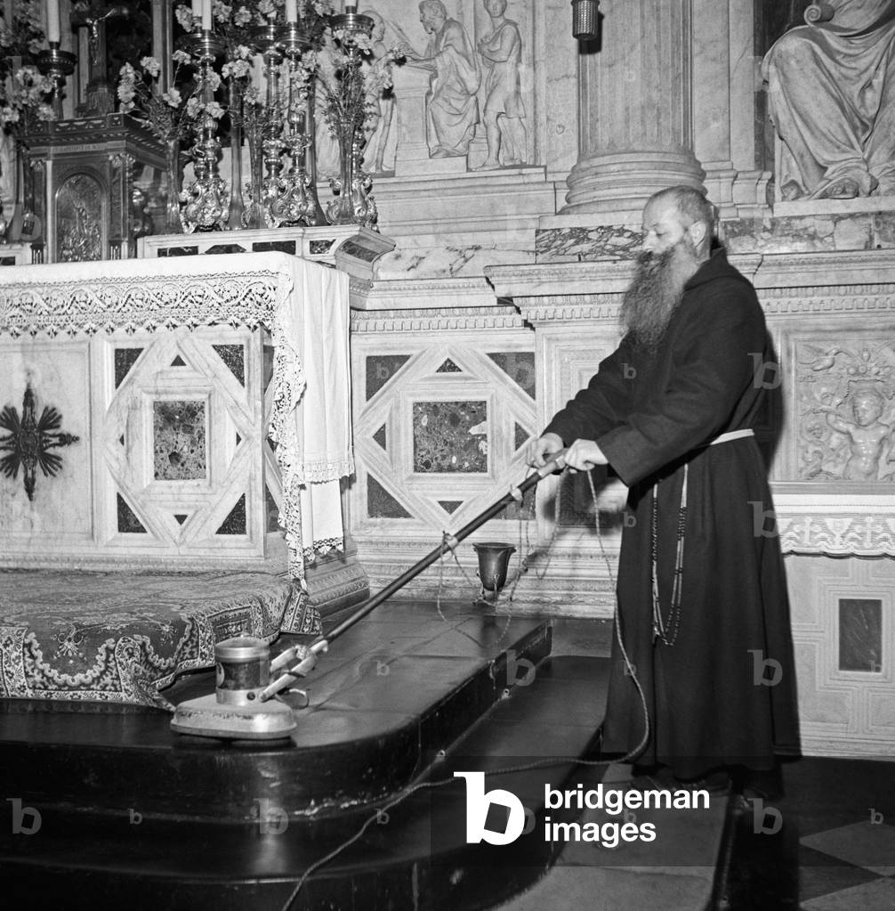 A friar vacuuming on the steps of the Holy House of Loreto, Loreto, Italy