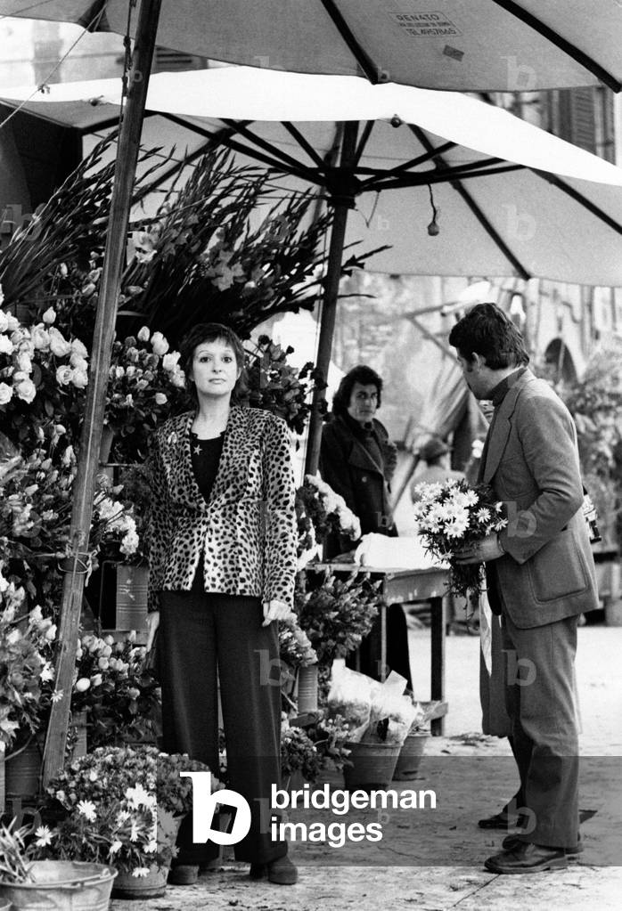 Adriana Asti beside a flower stall