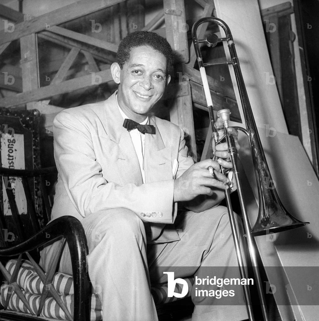 Louis Armstrong sitting with the trombone in his hands
