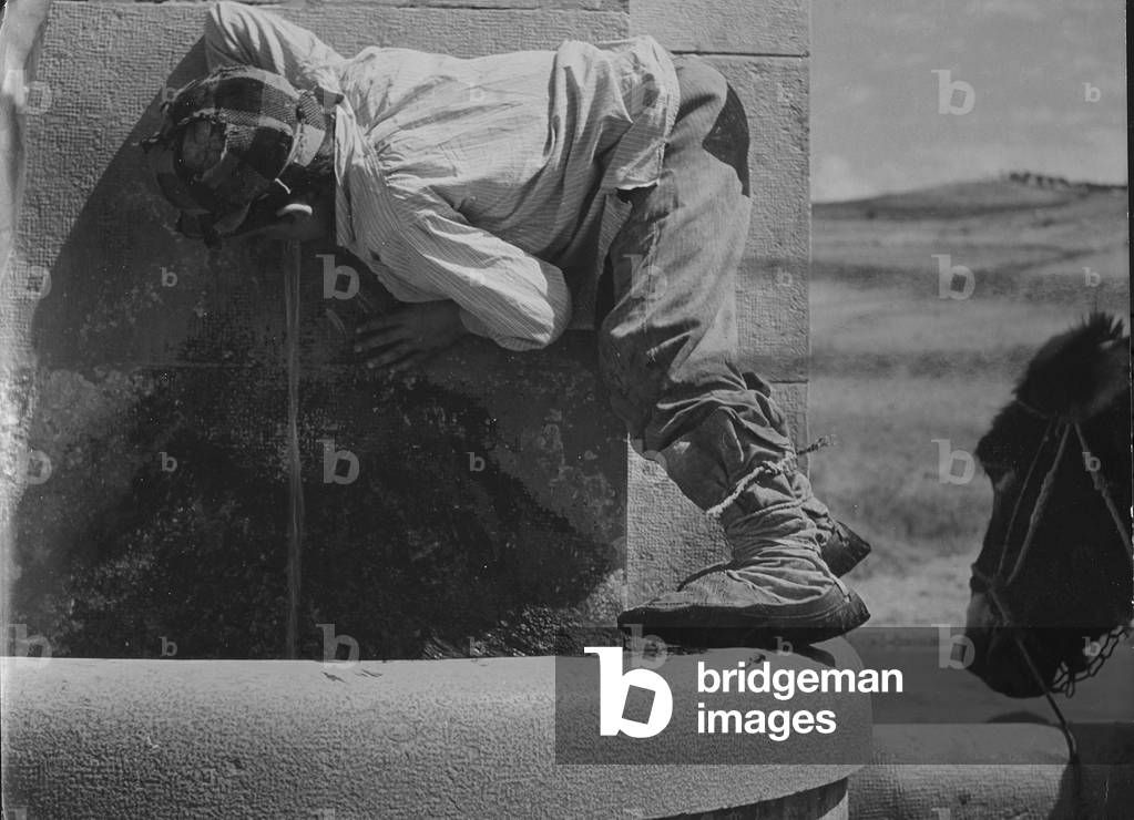 Little boy drinking at a fountain, Italy, 1950 (b/w photo)