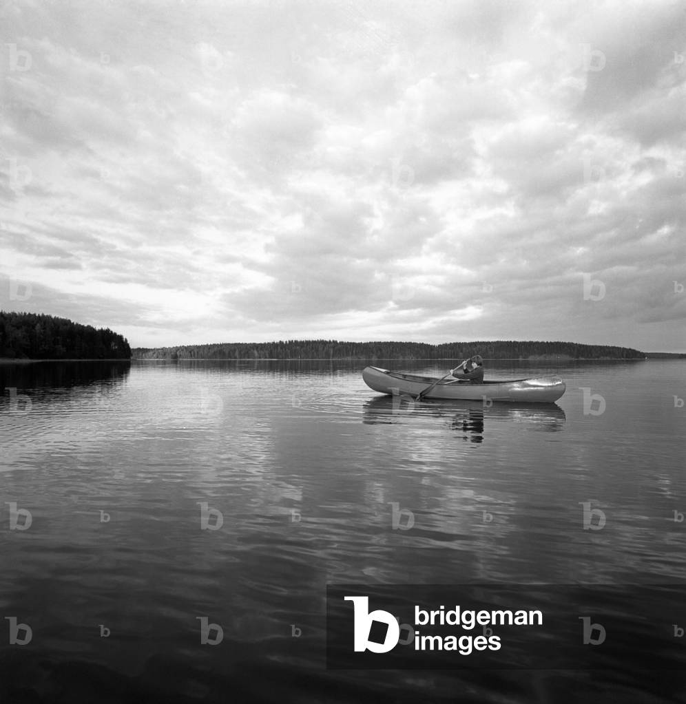 A young woma sailing a lake on a kayak, Finland, 1960s (b/w photo)