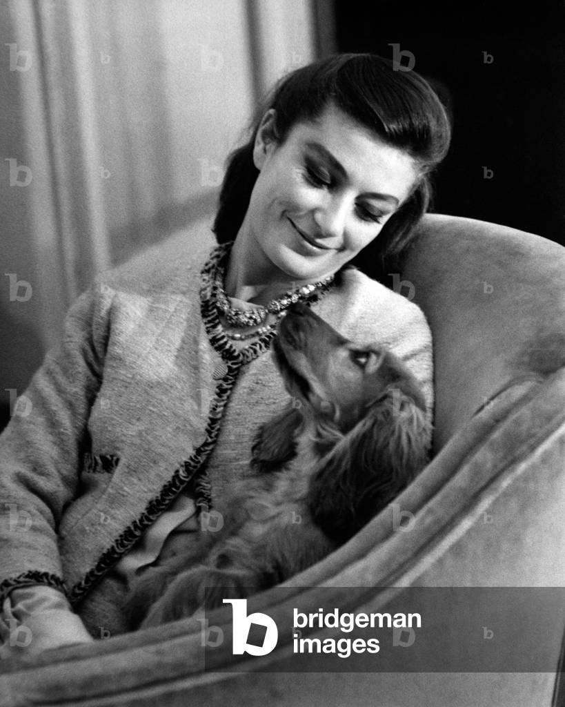 Anouk Aimée sitting in an armchair with her female dog Lulù, 1963 (b/w photo)