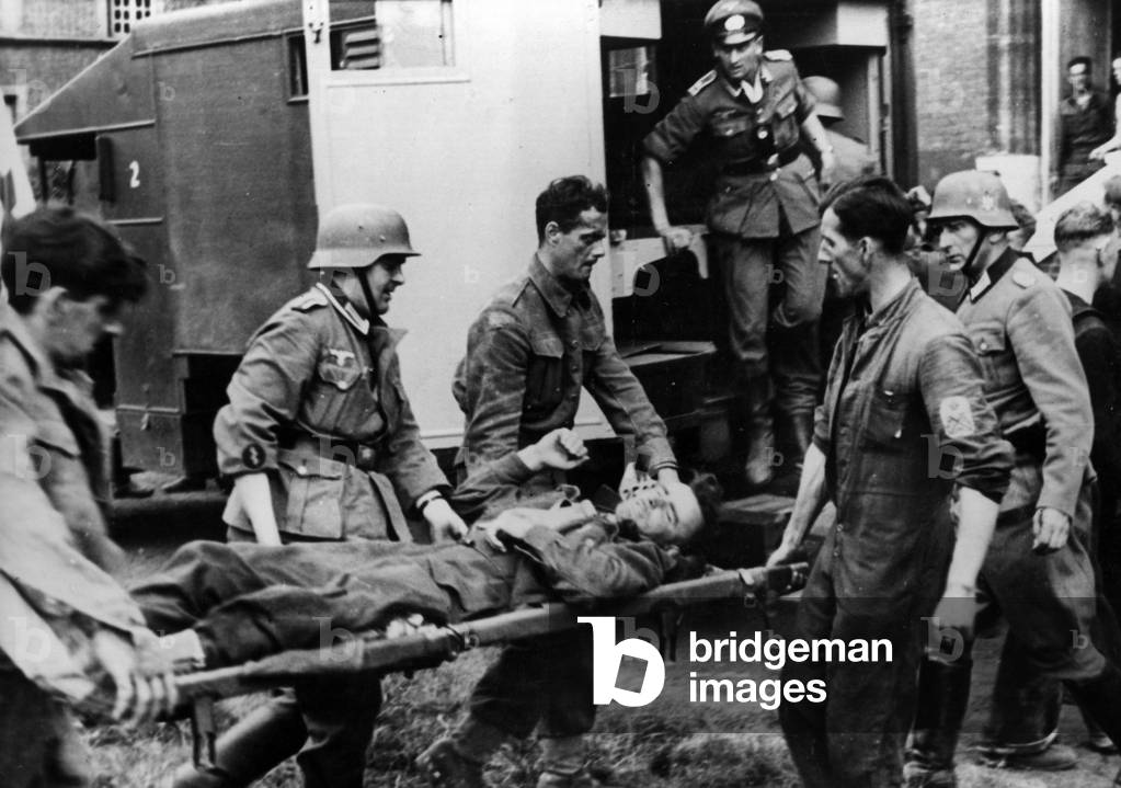 Captive Canadian soldiers carry a wounded officer