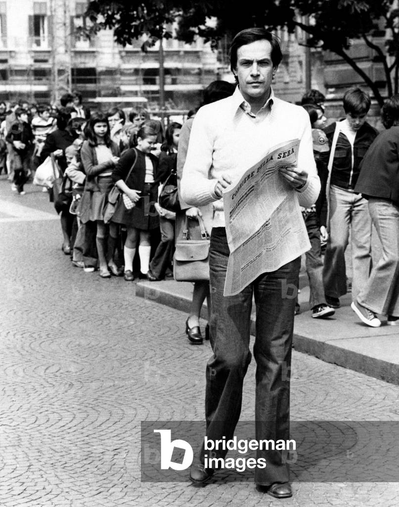 Roberto Bisacco flips through a newspaper during a walk