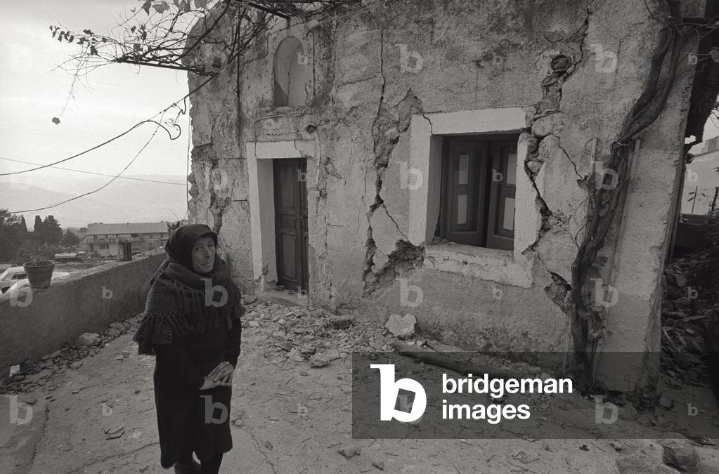 A woman in front of the collapse of her house, 1980 (b/w photo)