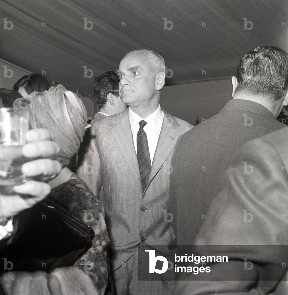 Alberto Moravia attending a cocktail party, Italy, 1963 (b/w photo)