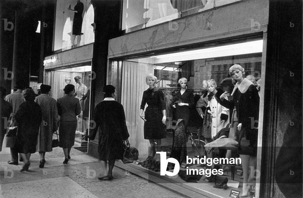 Women walk along the street watching shop windows, Milan, Italy