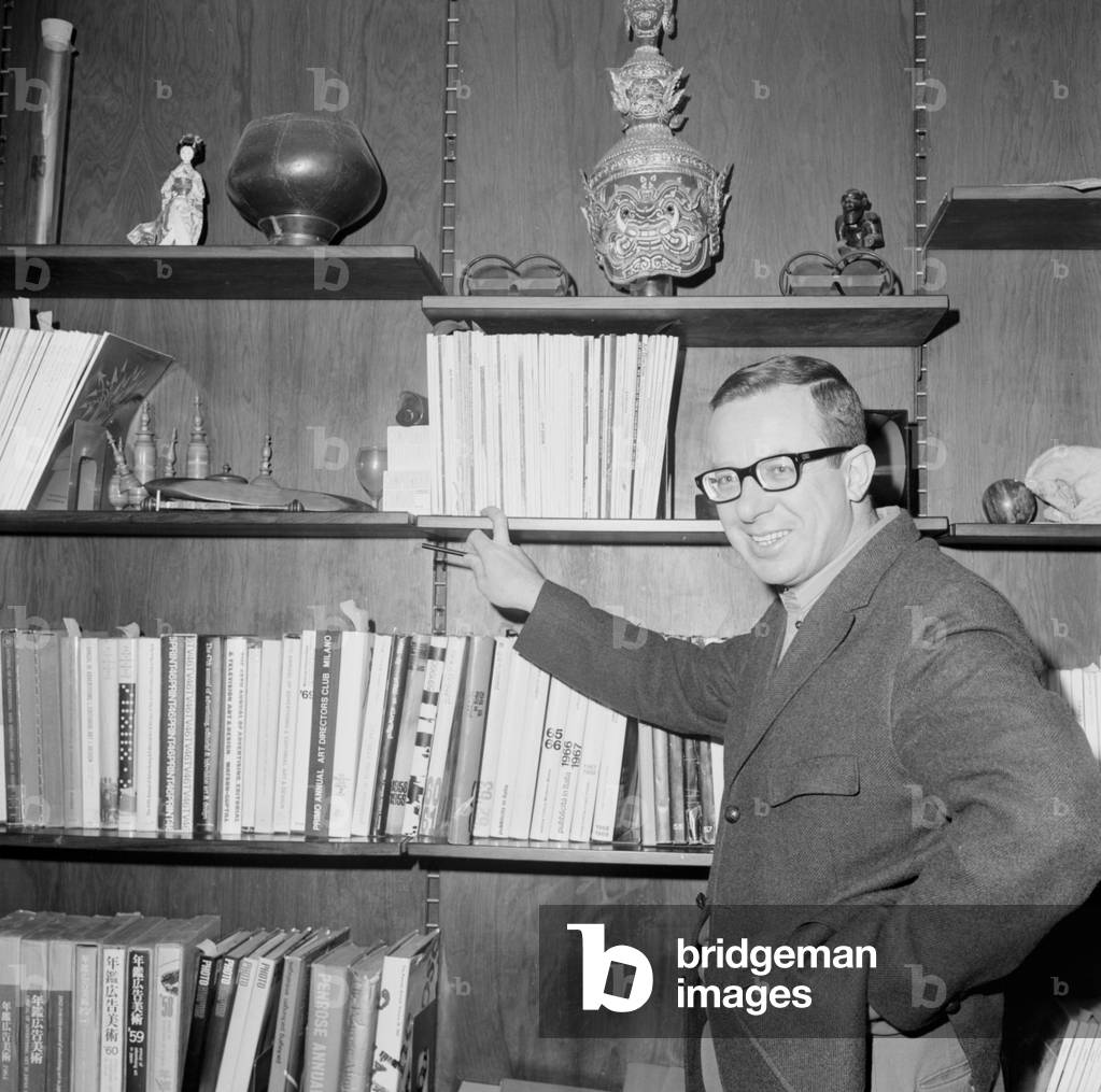 Luigi Veronelli smiling next to his library, 1970 (b/w photo)