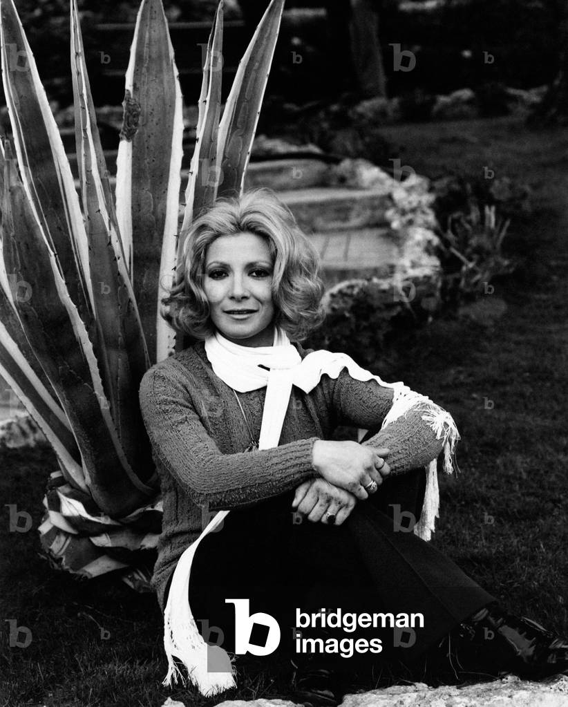Mariolina Cannuli is seated on the ground in front of an American aloe