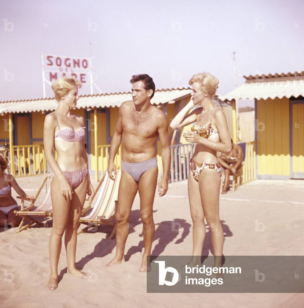 Alice and Ellen Kessler, twin sisters and german artistic duo, posing on the beach with Walter Chiari, italian actor, Italy, 1958 (photo)