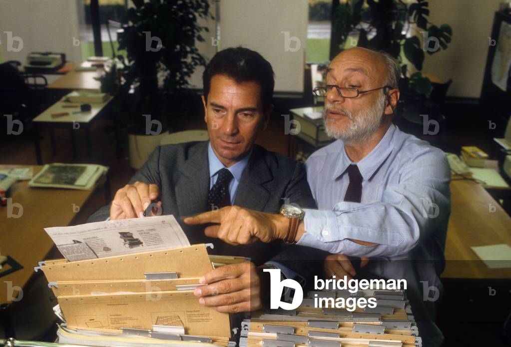 Carlo Rossella in front of a filing cabinet with another man