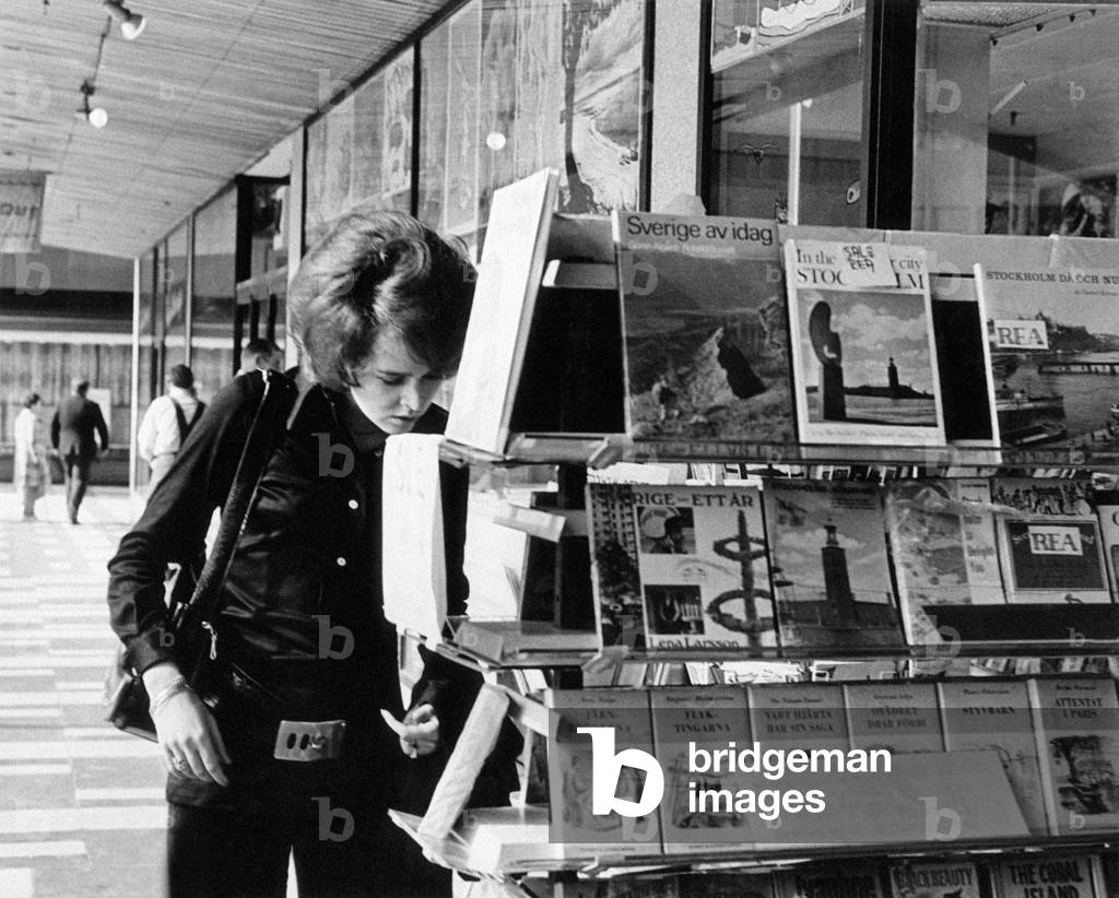 A girl looking at books exposed on a book stand, Stockholm, Sweden