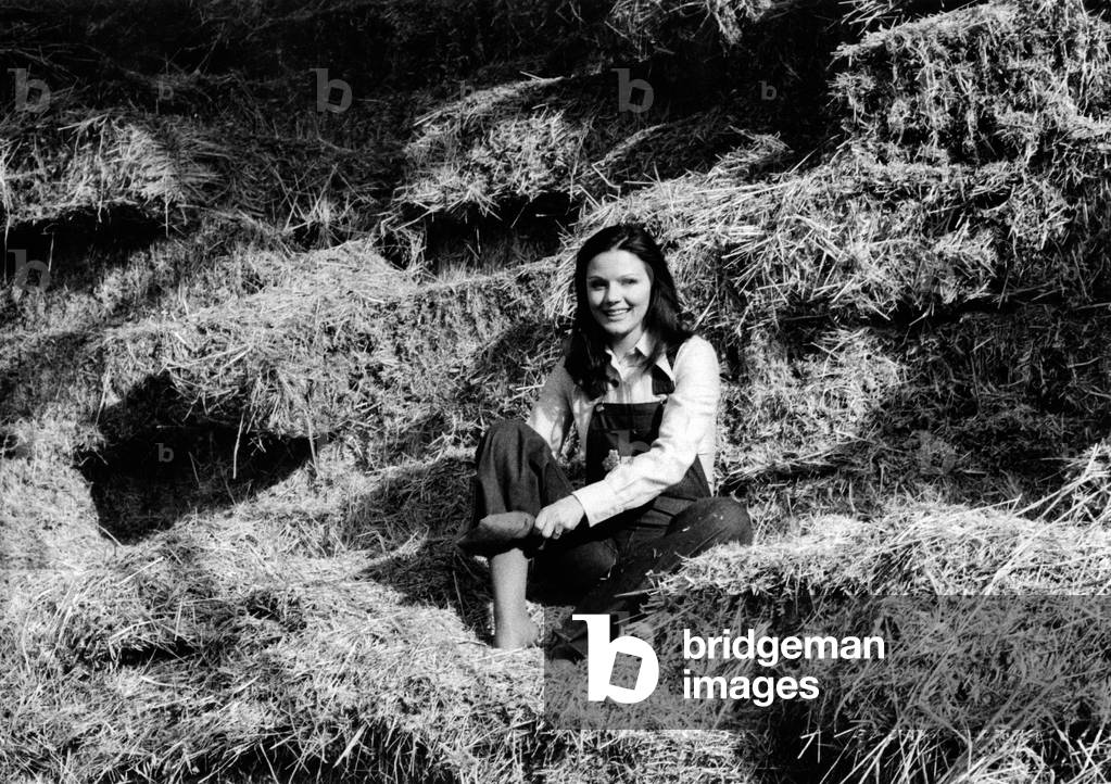Agostina Belli sitting on the hay