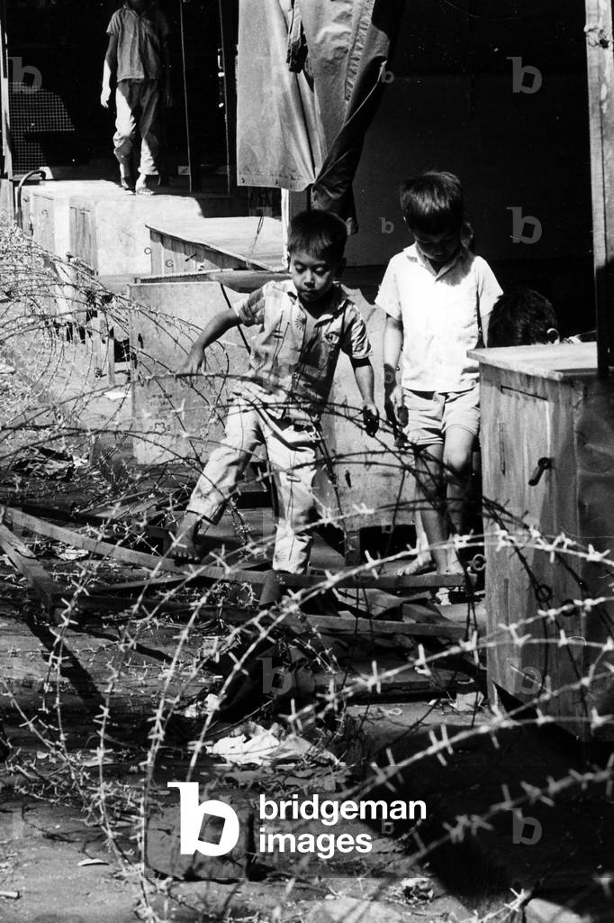 Some young children trying to make their way across the barbed-wire fence