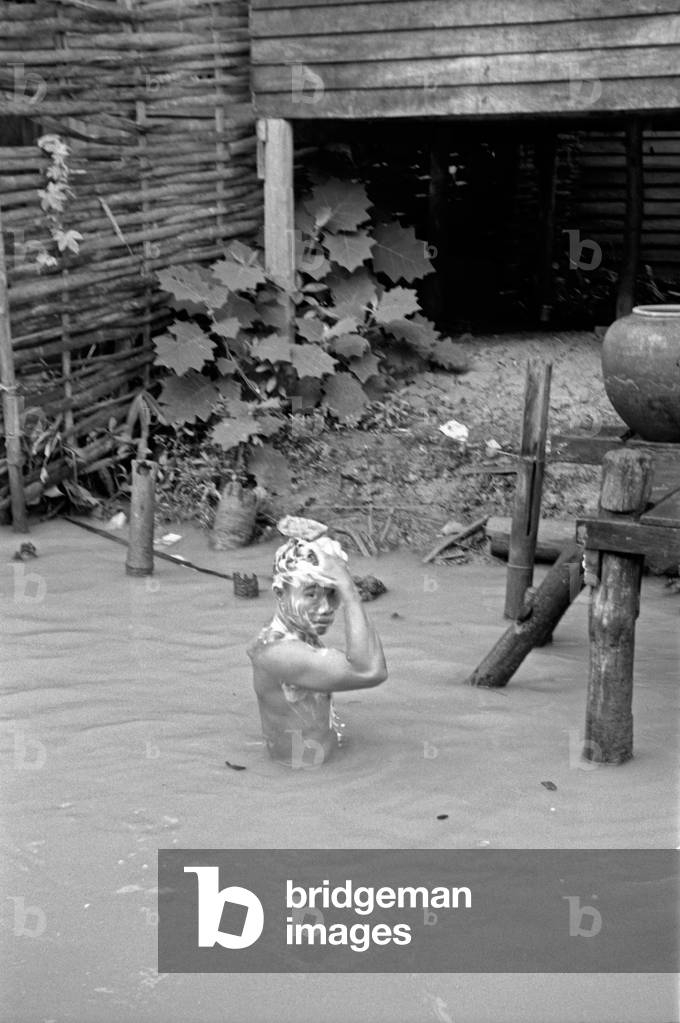 Thai boy washing his hair in a muddy river, Bangkok, 1961 (b/w photo)