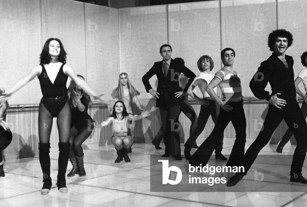 Italian TV host Pippo Baudo posing with the ballet company of a TV show, Italy, 1976 (b/w photo)