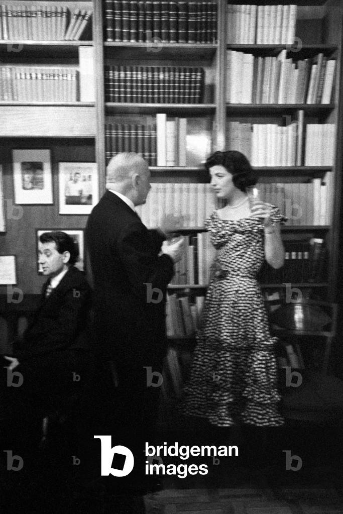 A woman talking to a man in front of a bookcase