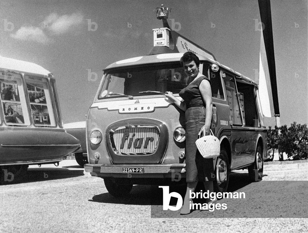 A woman poses in front of an advertising motor vehicle, Italy