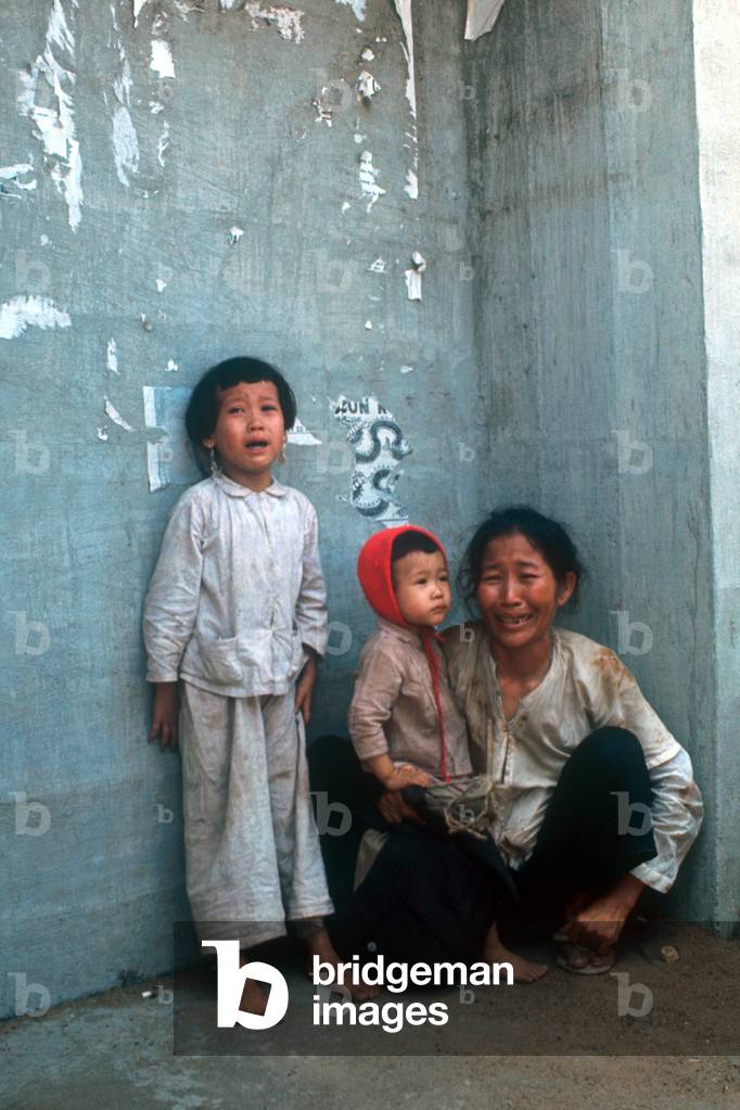 A Vietnamese woman is crying, together with two child