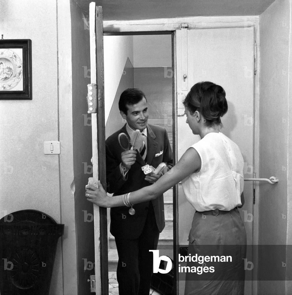 A woman opening her house to a door-to-door salesman, Italy